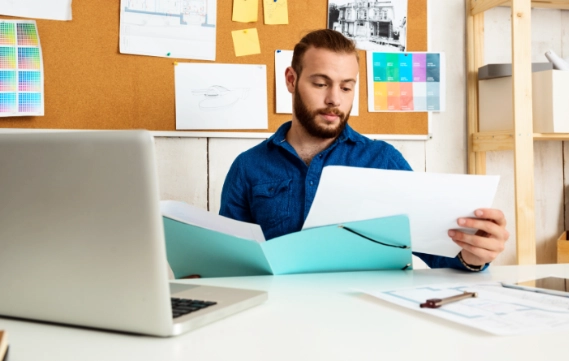 Man looking at print documents at desk